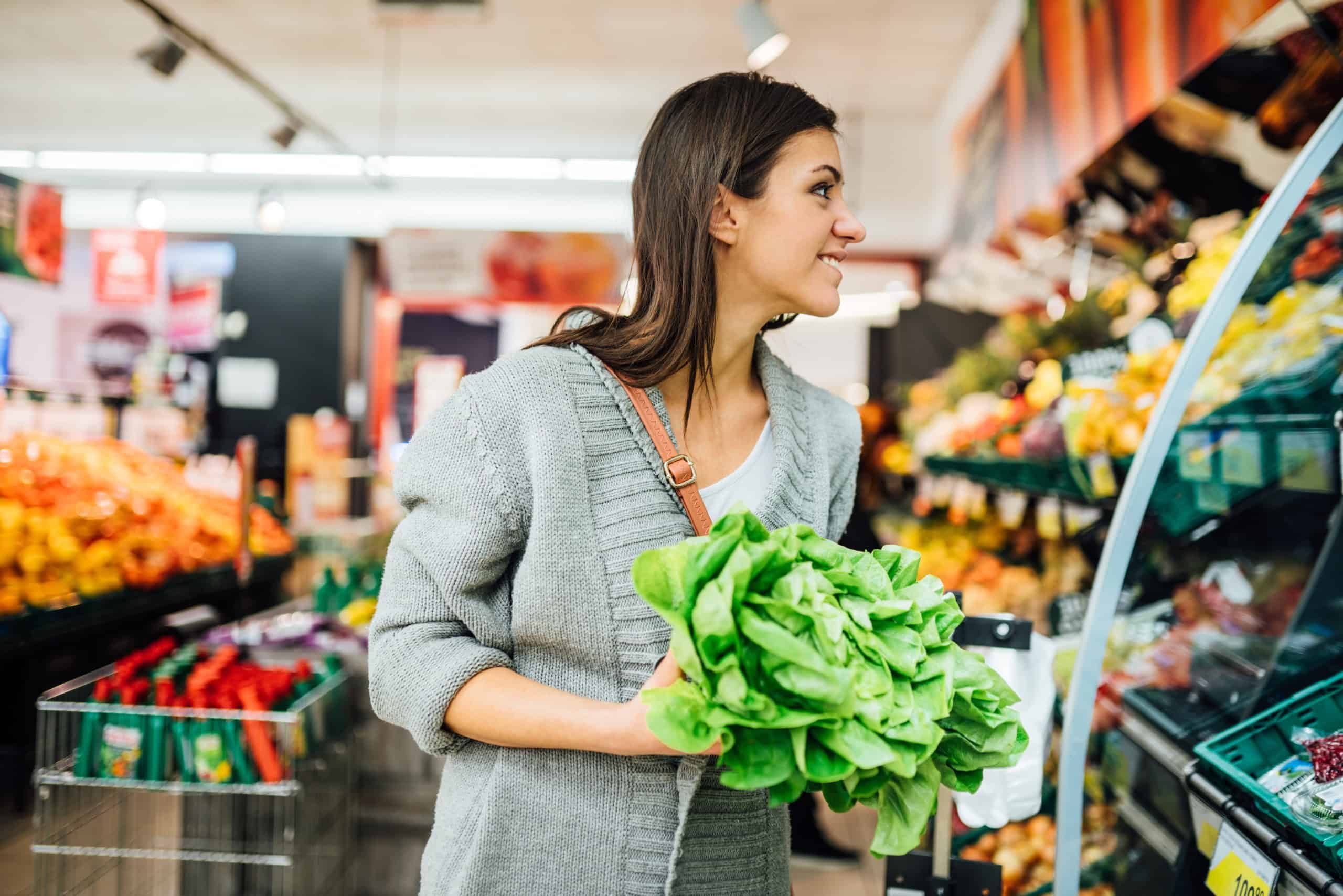Young woman holding lettuce in supermarket