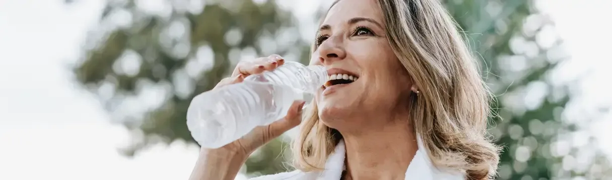 woman drinking from a water bottle after a workout outside